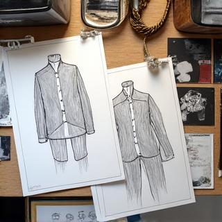 Sketsa desain busana pria di atas meja kerja desainer.